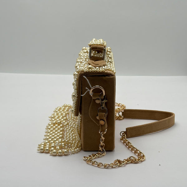 Beige handbag with pearl embellishments and a chain strap on a light gray background