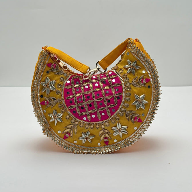 Decorative handbag with yellow, pink, and gold colors on a white background