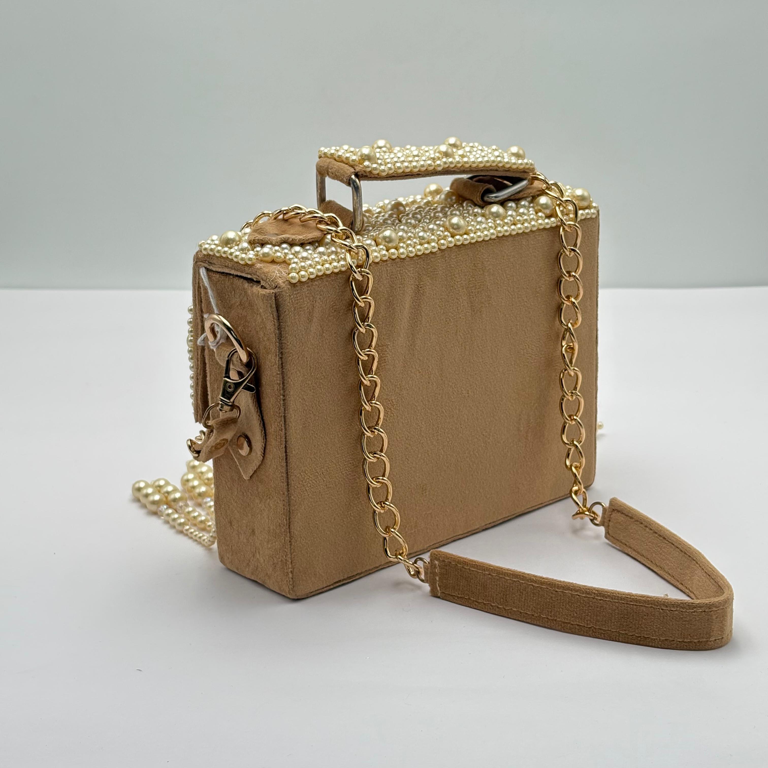 Beige handbag with pearl embellishments and a chain strap on a light gray background