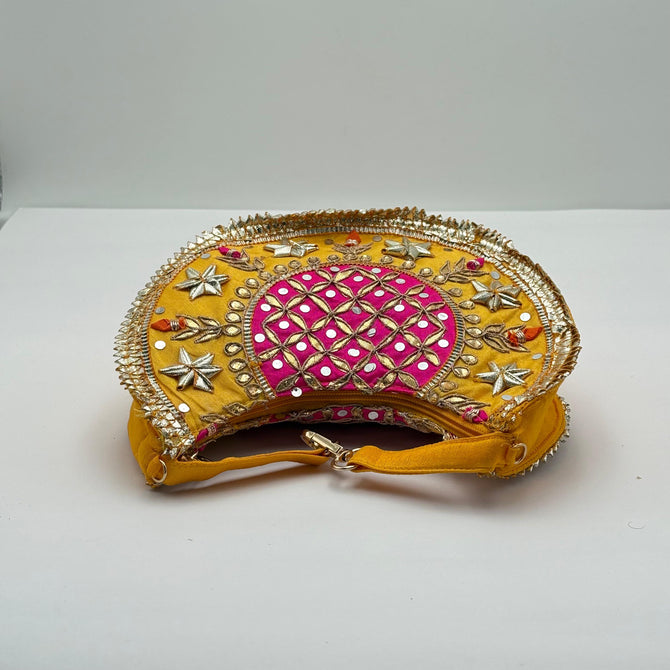 Decorative clutch bag with gold and pink design on a white background